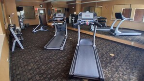 Une salle de sport équipée de tapis de course, d’appareils de musculation et d’un mur recouvert de miroirs.