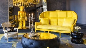 A luxurious room with a large mirror reflecting a golden statue, a yellow sofa, a black ottoman, and a chandelier. - Amazing experience with ocean views on Balboa Ave (Panamá)