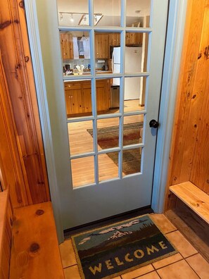 Una puerta de madera con un panel de vidrio que da a una cocina.