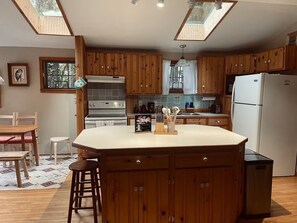 Una cocina con armarios de madera, una isla central, una estufa y un refrigerador.