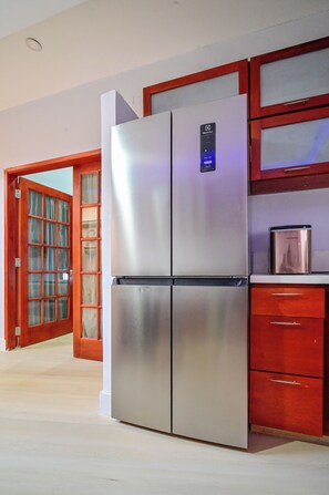A stainless steel refrigerator in a kitchen with wooden cabinets and a glass door. - Walled City 5BR Colonial Home, Private Jacuzzi, 2 Balconies, Sleeps 12 (Cartagena de Indias)