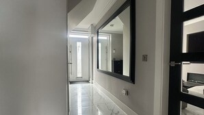 Ein Flur mit Marmorboden, einem großen Spiegel und einer Tür zum Schlafzimmer.