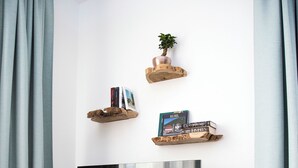 Un saló modern amb televisió plana sobre un moble de fusta, una petita planta i llibres en prestatgeries penjants.