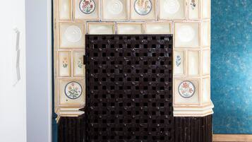 Une cheminée agrémentée d’un manteau décoratif en faïence et surmontée d’un grand vase.