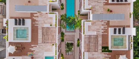 A modern hotel with a central pool, multiple balconies, and outdoor seating areas.