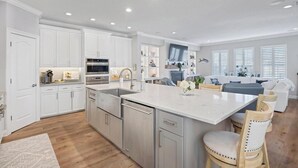 Une cuisine moderne avec des meubles blancs, des appareils en acier inoxydable et un îlot central doté de sièges.