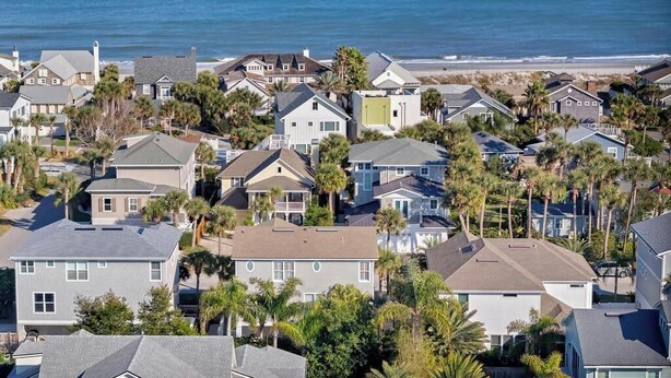 Un quartier résidentiel situé sur la côte, avec des maisons, dont certaines sont dotées de balcons, et une plage en arrière-plan.