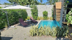 Un jardin avec une piscine, des chaises longues et une pergola.