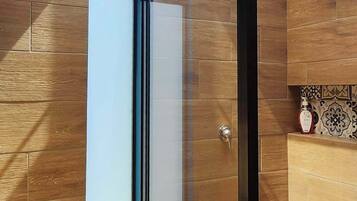A modern bathroom with a glass shower enclosure, wooden walls, and a white toilet.