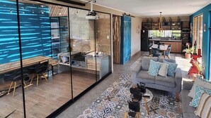 Un salon moderne comprenant un canapé, une table basse et une cloison en verre qui sépare l’espace de vie de la cuisine.