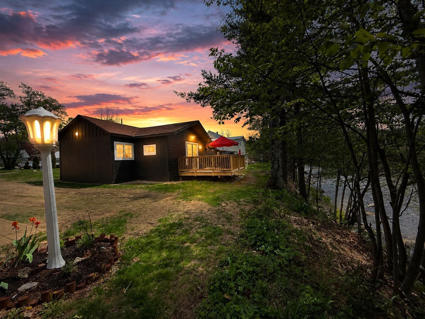 Une cabane en bois dotée d’une terrasse, d’un porche et d’un lampadaire.