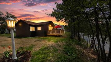 Une cabane en bois dotée d’une terrasse, d’un porche et d’un lampadaire.