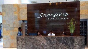 Un comptoir d’accueil avec un panneau en bois foncé sur lequel est inscrit le nom « Samaria Club de Playa ».