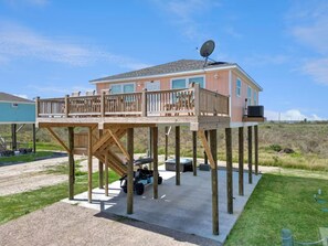 A two-story house with a deck, a satellite dish, and a vehicle parked in front. - Sunset Bellini - Hot Tub, Golf Cart, Dog Friendly! (Bolivar Peninsula)