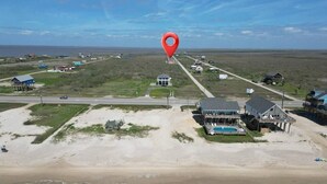 An aerial view of a coastal area with a large house, a swimming pool, and a beach. - Sunset Bellini - Hot Tub, Golf Cart, Dog Friendly! (Bolivar Peninsula)
