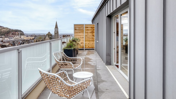 A balcony with wicker chairs and a small table, overlooking a cityscape with historical buildings. - Les Mathurins, F2 unique terrasse, parking et sport (Rouen)