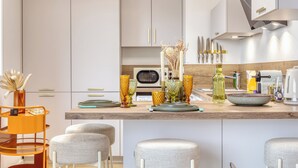 A modern kitchen with white cabinets, a wooden countertop, and a bar area with stools. - Les Mathurins, F2 unique terrasse, parking et sport (Rouen)