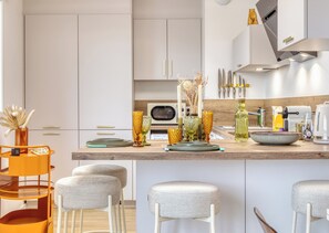 Une cuisine moderne avec des meubles blancs, un plan de travail en bois et un coin bar avec des tabourets.