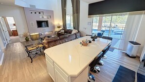 A modern kitchen with a large island, built-in appliances, and a dining area with a view of the outdoors. - Tinkerbells Suites, 4m Disney, 6/5.5 Large pool+Spa, 4 themed masters, pets (Kissimmee)