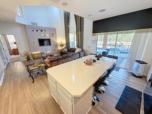 A modern kitchen with a large island, built-in appliances, and a dining area with a view of the outdoors. - Tinkerbells Suites, 4m Disney, 6/5.5 Large pool+Spa, 4 themed masters, pets (Kissimmee)