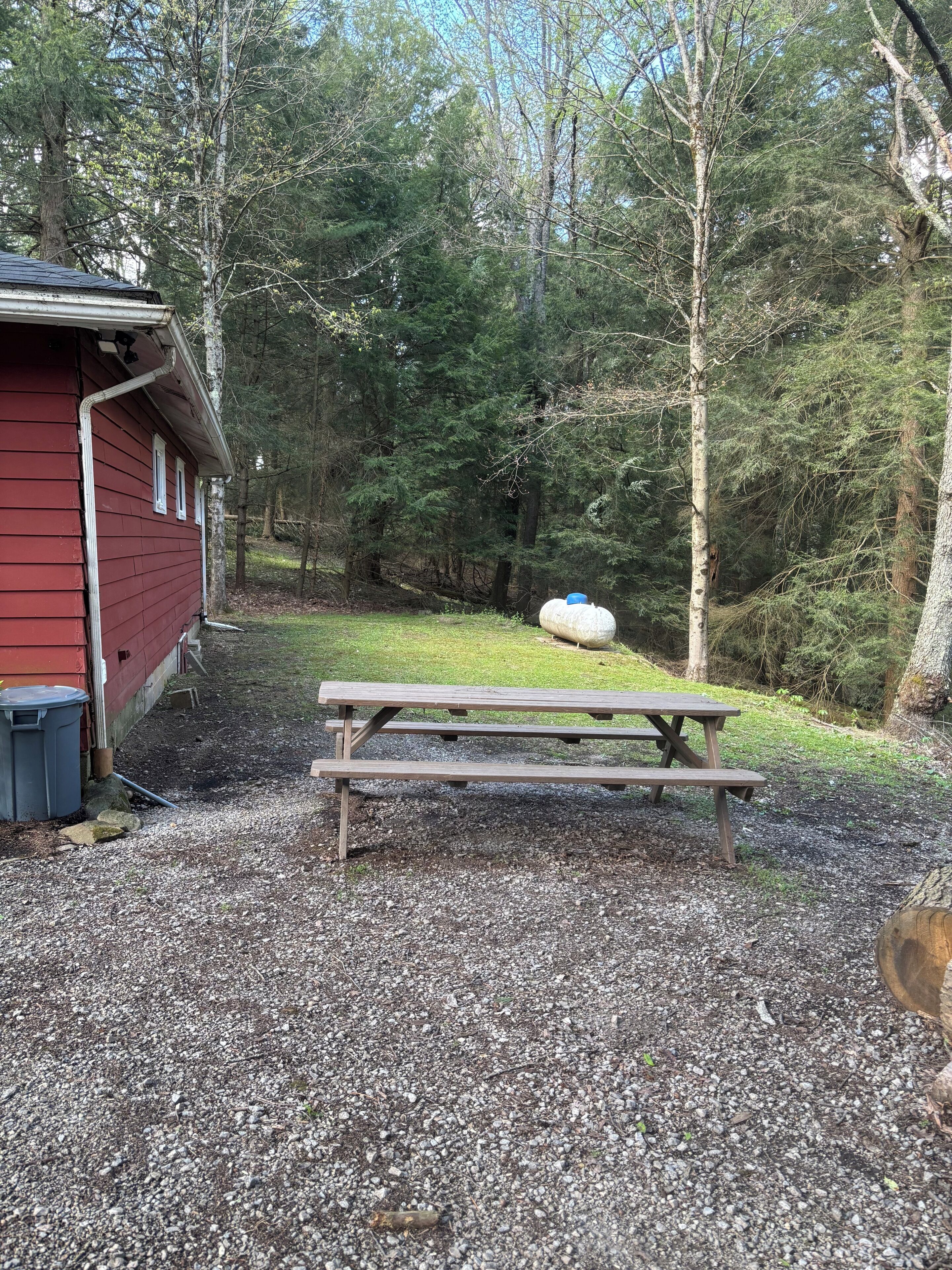 A red building with a gravel ground, a picnic table, and a large white object in the background.