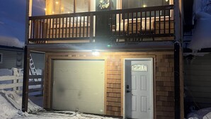 A two-story house with a balcony, a garage, and a snow-covered driveway.