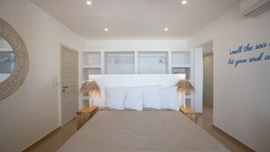 Un dormitorio con una cama grande, paredes blancas, un espejo y una cita en la pared.