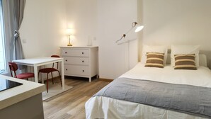 A bedroom with a bed, bedside table, lamp, and a desk with a chair. - Modern Bright Studio near Parc de la Villette for2 (Paris)