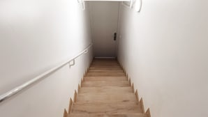 A wooden staircase with white walls and a handrail, leading to a door at the top. - Modern Bright Studio near Parc de la Villette for2 (Paris)