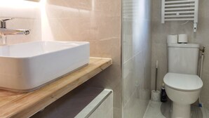 A modern bathroom with a white sink, a toilet, and a glass shower enclosure. - Modern Bright Studio near Parc de la Villette for2 (Paris)