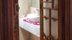 Ein Badezimmer mit Waschbecken, Spiegel und einer Holztür mit geometrischem Muster.