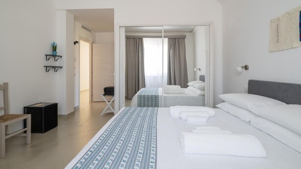 A modern hotel room with a large bed, a desk, and a chair. There is a door leading to another room. - Room Maria Lai(I Centenari Longevity Rooms) Property located 1 km from the beach (Lotzorai)