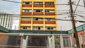 A tall, yellow and red building with multiple windows and a gated entrance. - Studio Barreto Leme 12 (Campinas)