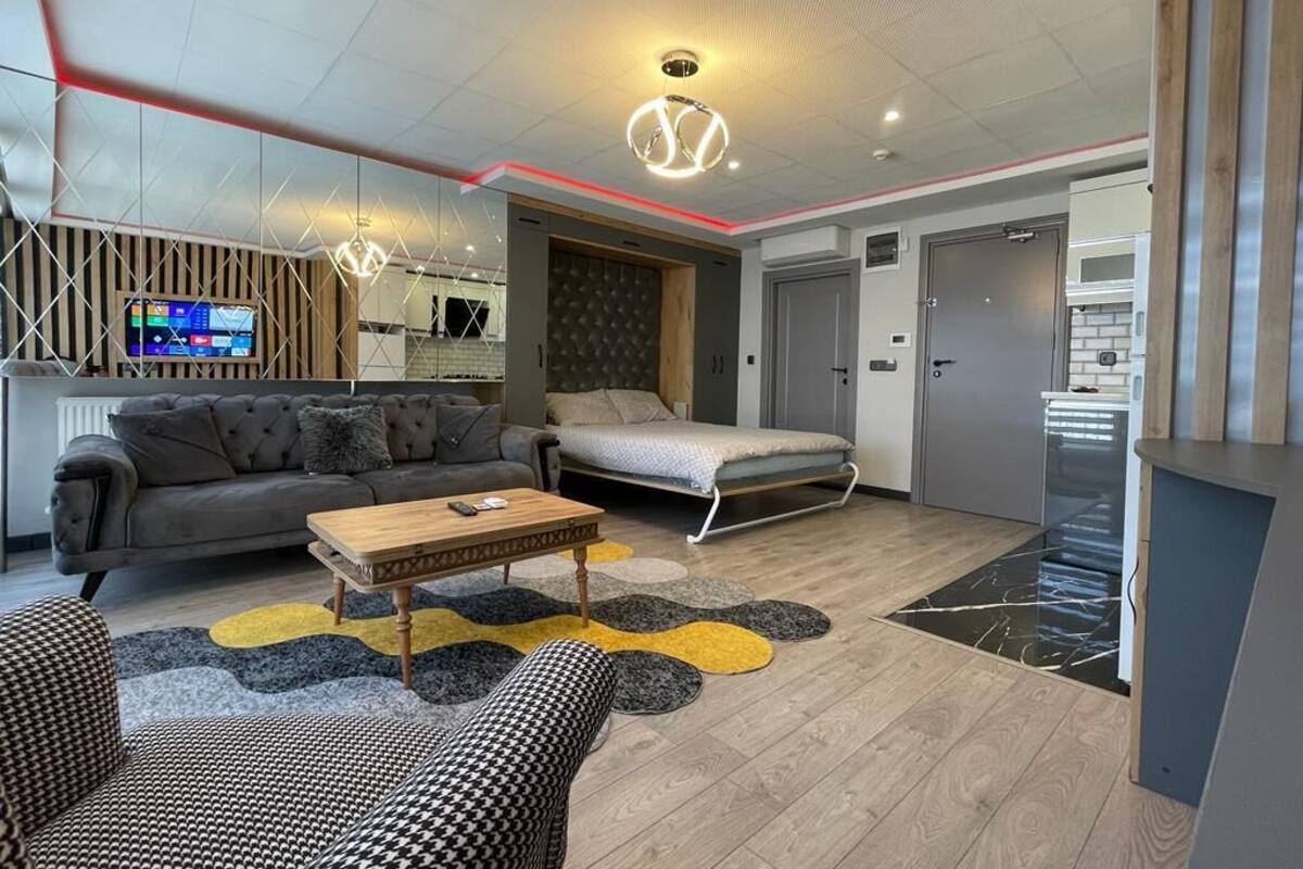 Ein modernes Wohnzimmer mit Sofa, Couchtisch, Fernseher und Küchenzeile inklusive Mikrowelle.