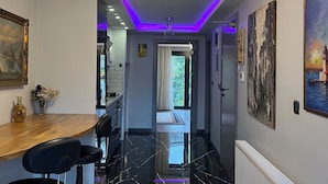 A modern kitchen with a wooden countertop, black bar stools, and a pendant light. - Ortaköy Suit (İstanbul)
