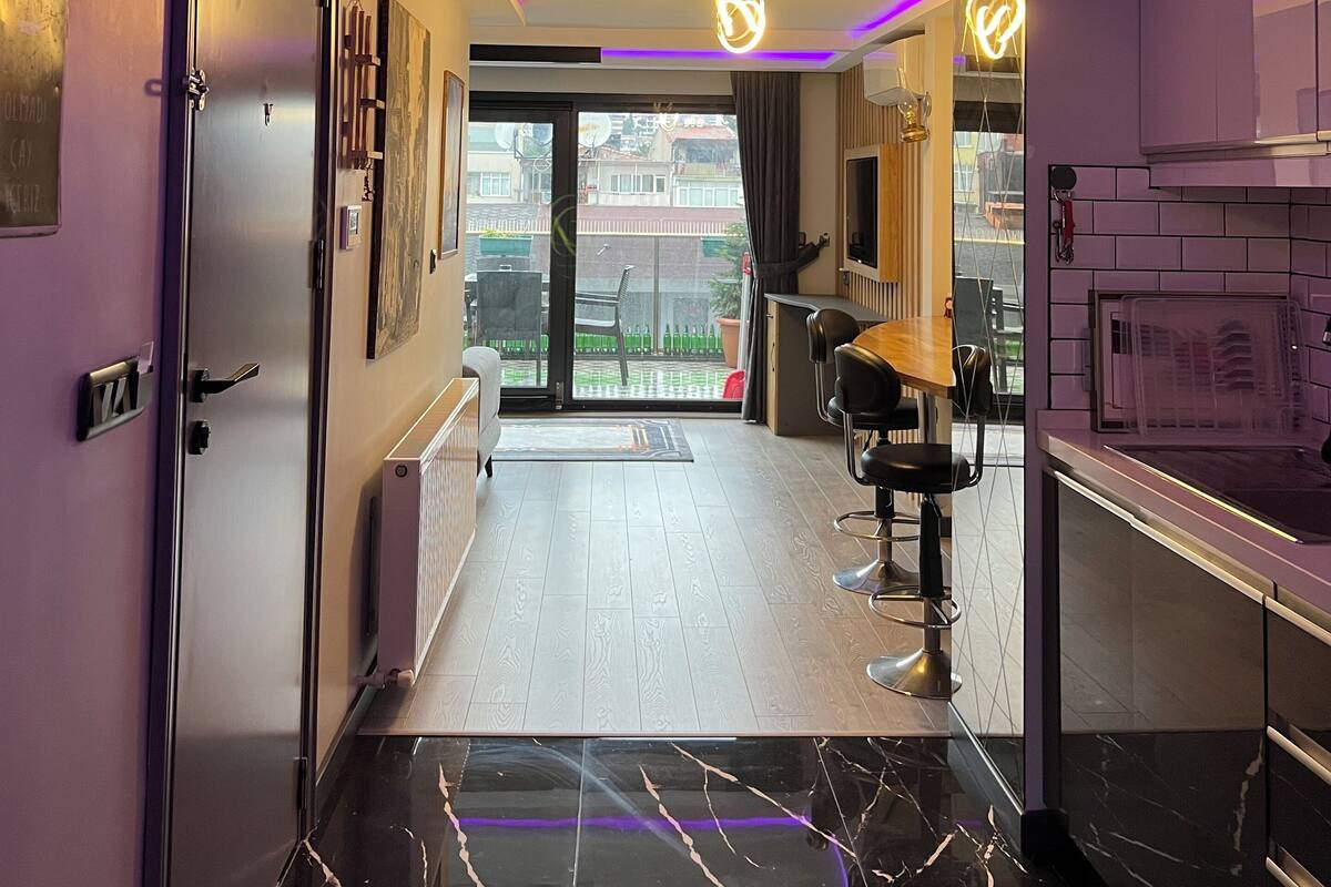 Ein modernes Interieur mit Küchenbereich, Essplatz und Blick durch eine Glastür nach draußen.