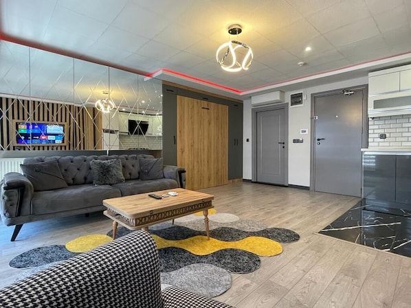 A modern living room with a grey sofa, a wooden coffee table, and a patterned rug.