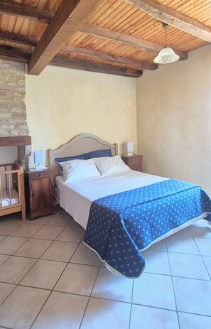 Une chambre avec un lit, des tables de chevet en bois, un mur en briques et un plafond en bois.