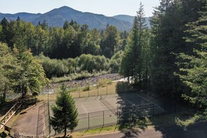 A tennis court surrounded by dense forest and mountains in the background. - Cozy Cabin: Relax in Hot Tub Overlooking Creek (Rhododendron)