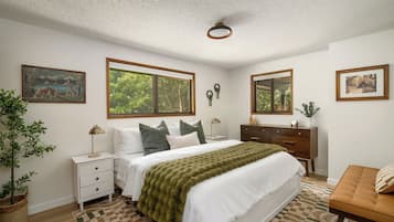 A bedroom with a bed, nightstands, a dresser, a mirror, and two framed pictures on the wall.