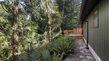 Una terraza de madera que conduce a una cabaña rodeada de un bosque denso.