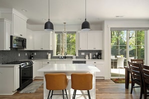 Cocina moderna con armarios blancos, salpicadero blanco y negro y dos lámparas colgantes.