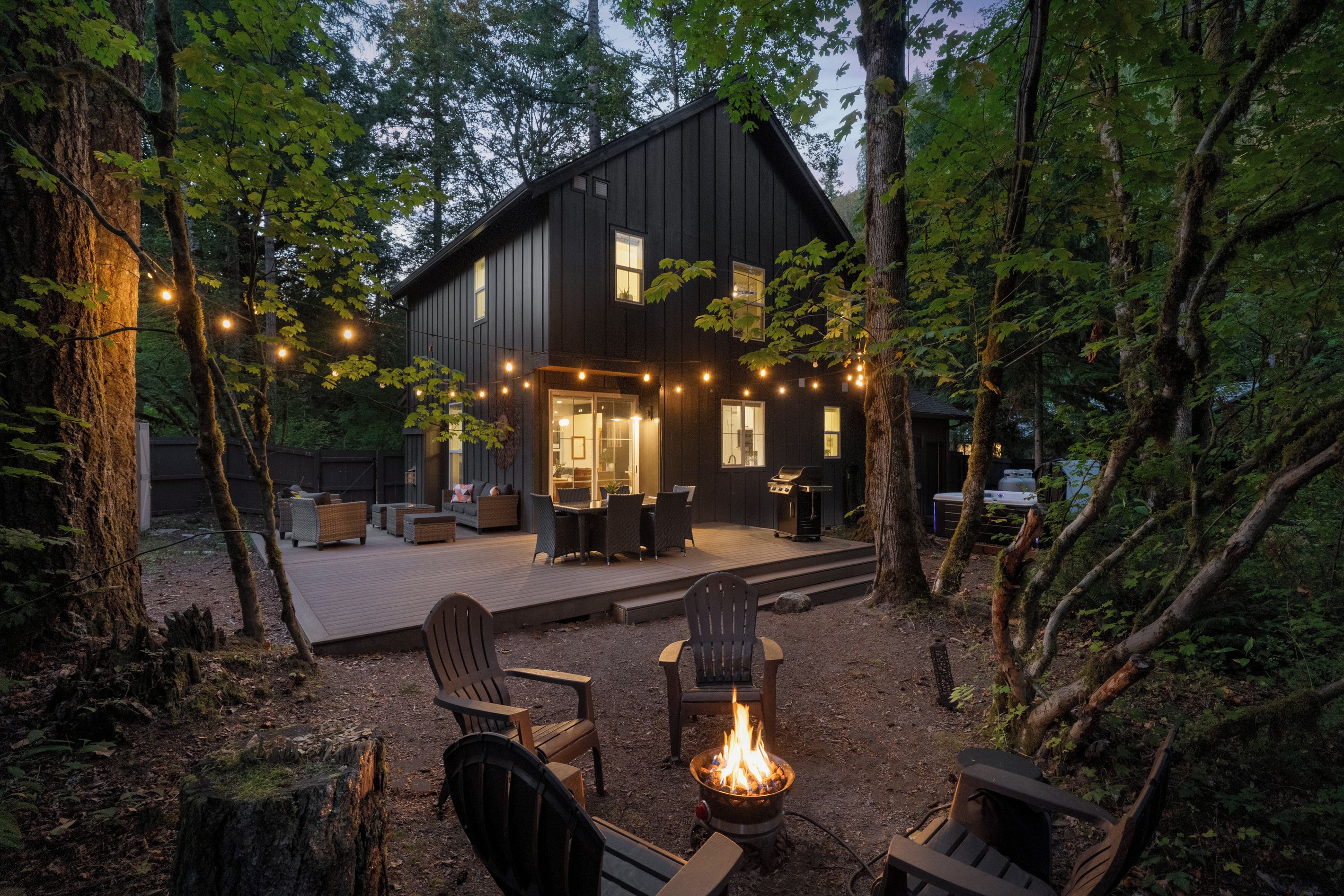 A modern house with a deck, outdoor furniture, and a fire pit.
