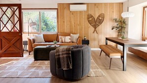 Un soggiorno moderno con pannello decorativo in legno, un divano, un tavolino, una panca e un tavolo da pranzo.