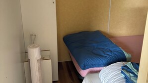 A small, compact room with a bed, a standing heater, and a wooden floor. - Fully equipped mobile home for 4–6 people in Hourtin, between the lake, the forest, and the ocean🏖️ (Hourtin)