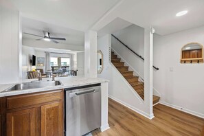 Une cuisine moderne équipée d’un lave-vaisselle, un coin repas avec une table et des chaises, et un escalier menant à un autre niveau.