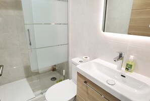 Ein modernes Badezimmer mit Duschkabine aus Glas, einer weißen Toilette und einem Waschbecken mit Spiegel.