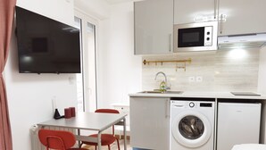 Een kleine keuken met een magnetron, wasmachine en spoelbak.
