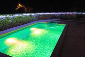 A swimming pool with a stone wall and a lighted edge. - Villa Leen Dubrovnik – Your Private Escape with a Pool and Panoramic Views (Đurinići)