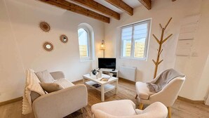 A living room with a sofa, armchair, coffee table, TV, and decorative items. - New - small cosy cottage for 4 near the sea (Landunvez)